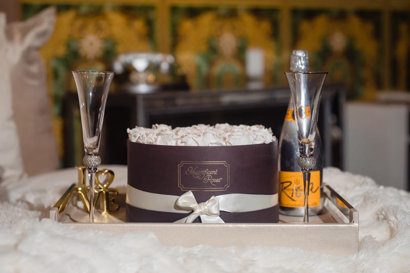 closeup of box of white roses with champagne and two glasses